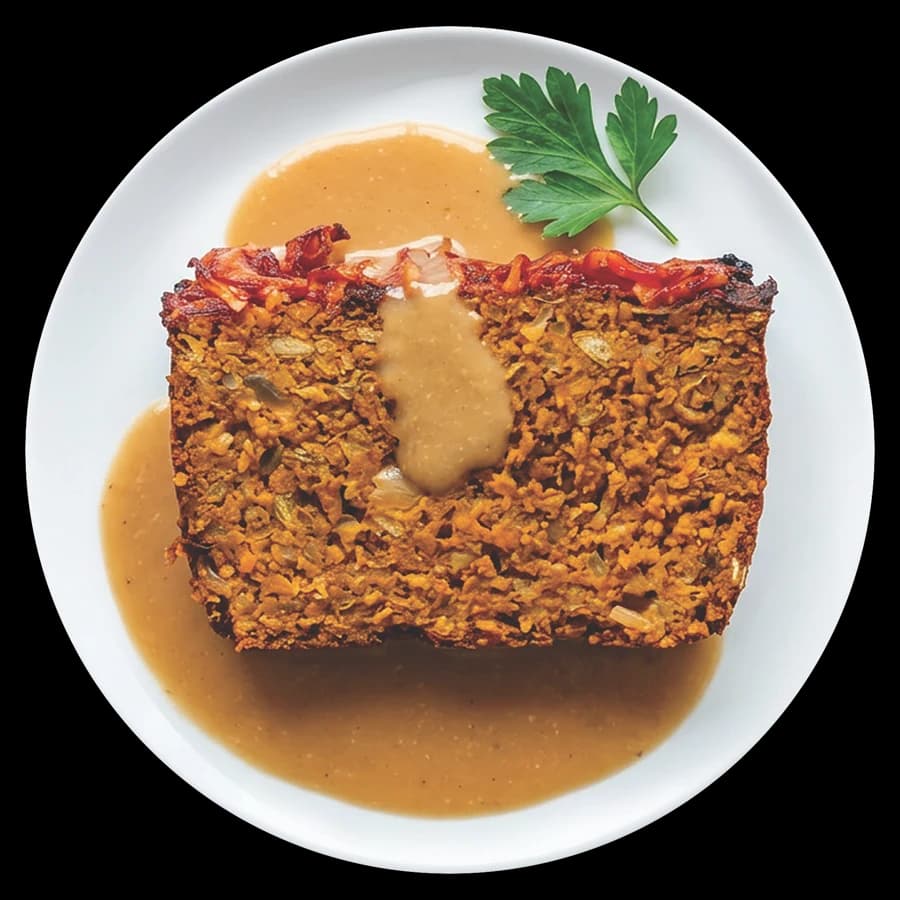 Sliced lentil almond veggie loaf with savory gravy and parsley